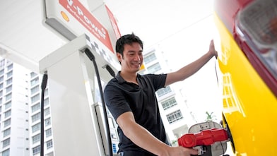 Bir adam benzin pompasında arabasının deposunu dolduruyor