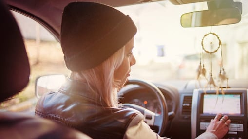 Genç bir kadın otomobilinin navigasyon ekranından yol tarifini kontrol ediyor