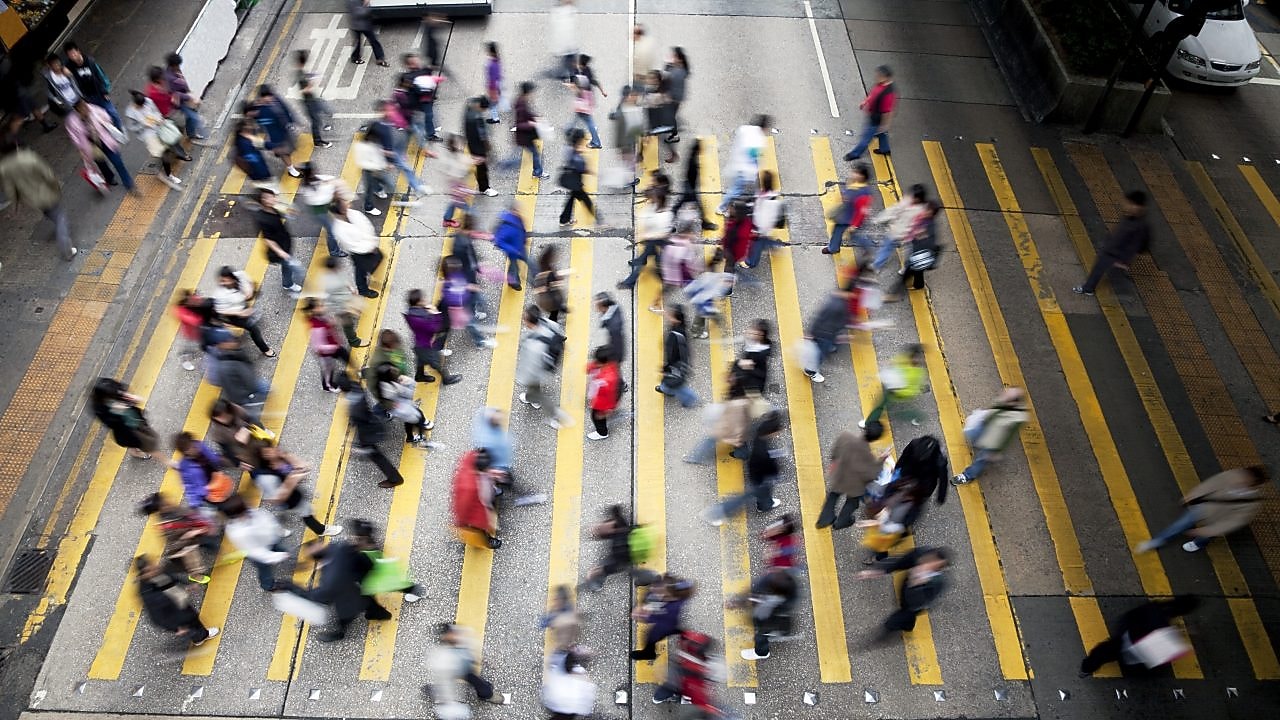 Hong Kong'da işlek bir caddeden karşıya geçen insanlar